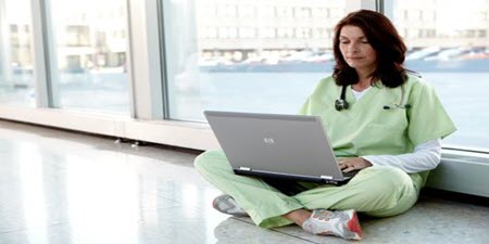 Clinician sitting on the floor reading laptop
